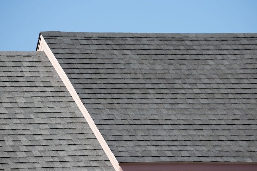 Gray shingled roof with a diagonal white ridge against a blue sky