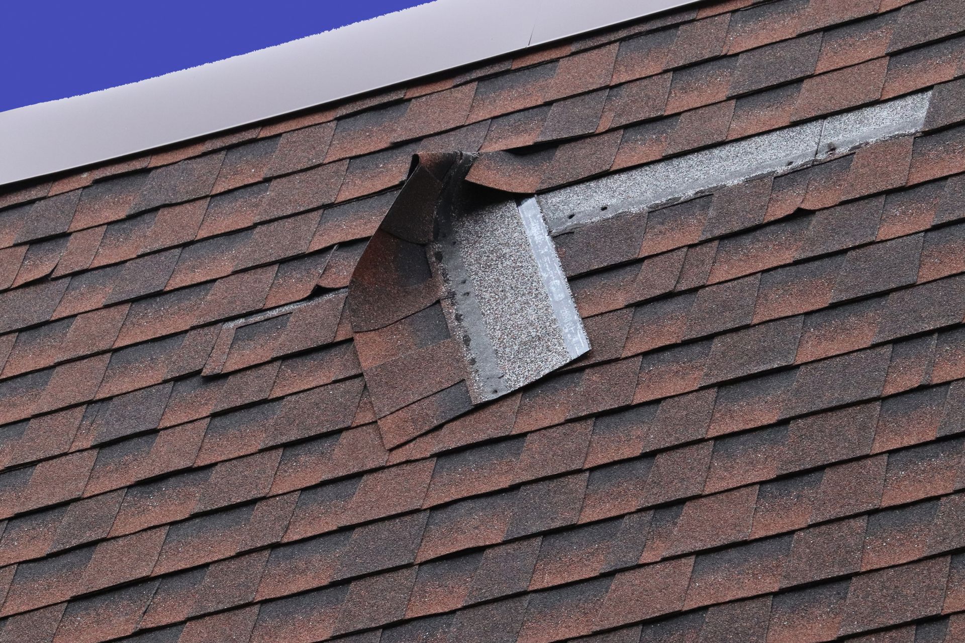 Damaged shingled roof with a bent metal vent pipe sticking out near the peak Damaged shingled roof with a bent metal vent pipe sticking out near the peak