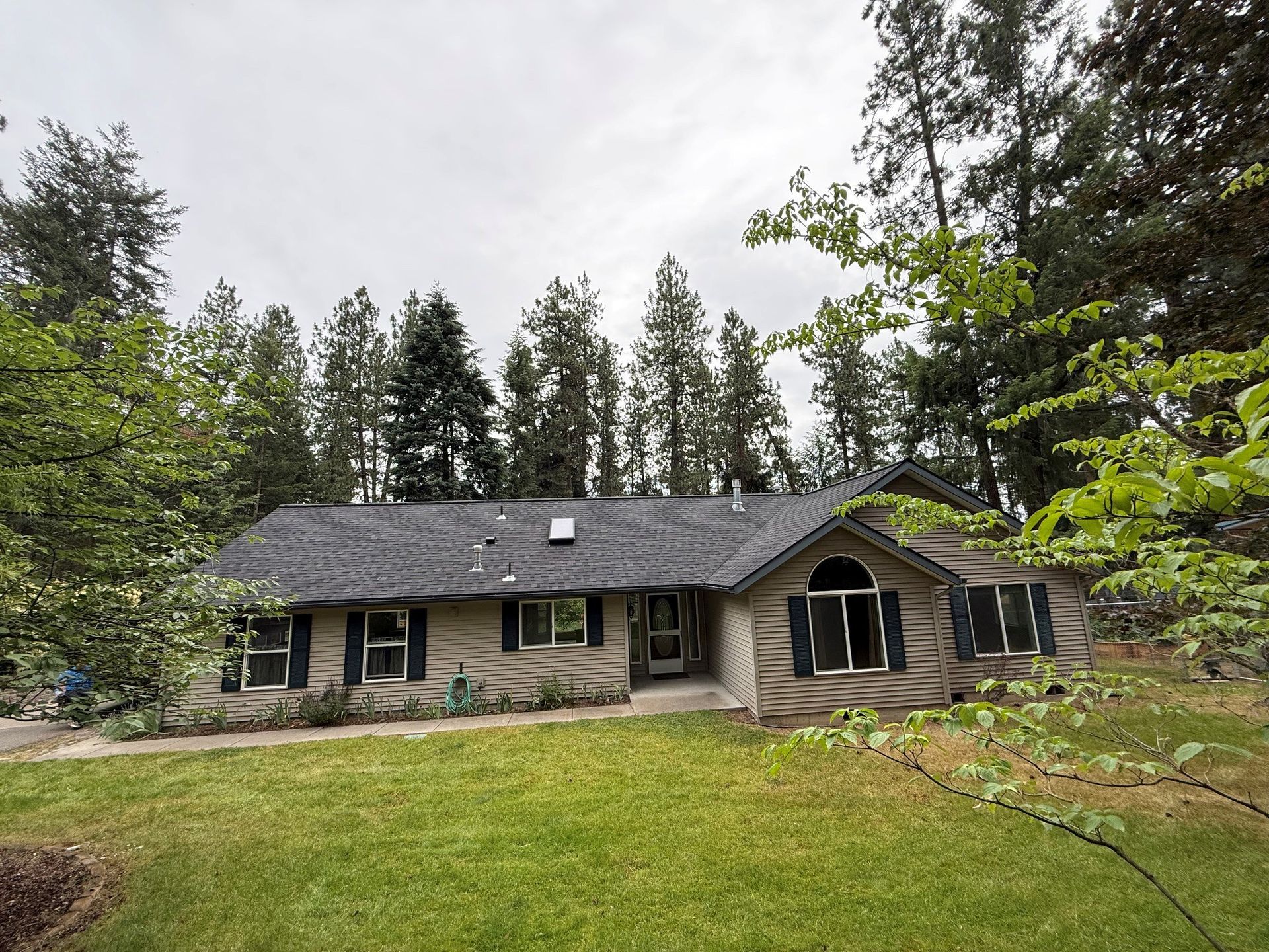 Gray slate roof with two dormer windows on a white house exterior Gray slate roof with two dormer windows on a white house exterior