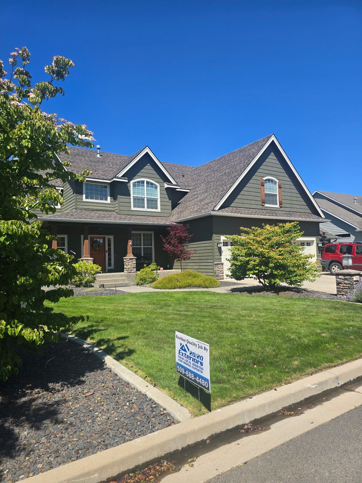 Blue sky above a beige house with white trim and leafless trees on the left