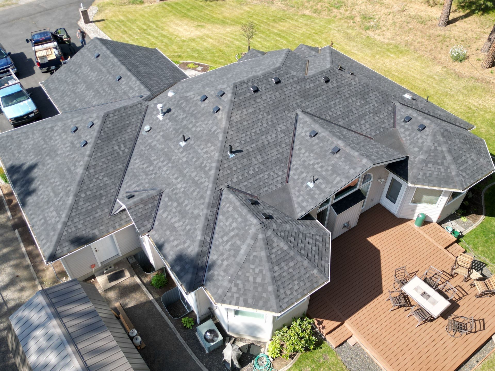 Aerial view of a large gray-roofed suburban house with a patio and backyard.