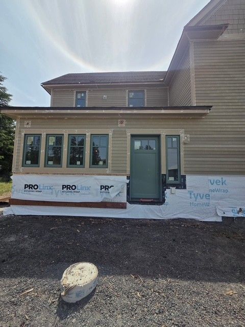 House exterior under renovation with new siding, windows, and door partially installed