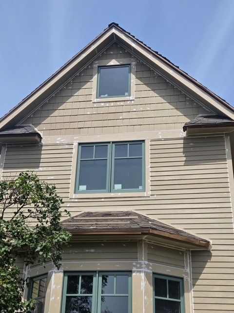 Front view of a beige two-story house with gray trim and a steep gabled roof
