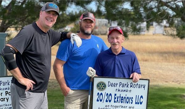 Three men posing outdoors with a Deer Park Rotary and 20/20 Exteriors LLC sign Three men posing outdoors with a Deer Park Rotary and 20/20 Exteriors LLC sign
