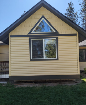 Exterior wall with gray siding, a white window, OSB sheathing, and a ladder on the right. Exterior wall with gray siding, a white window, OSB sheathing, and a ladder on the right.