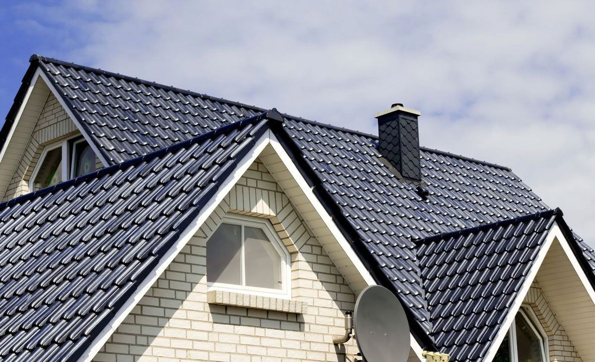 Worker in orange helmet using a power tool on a tiled roof