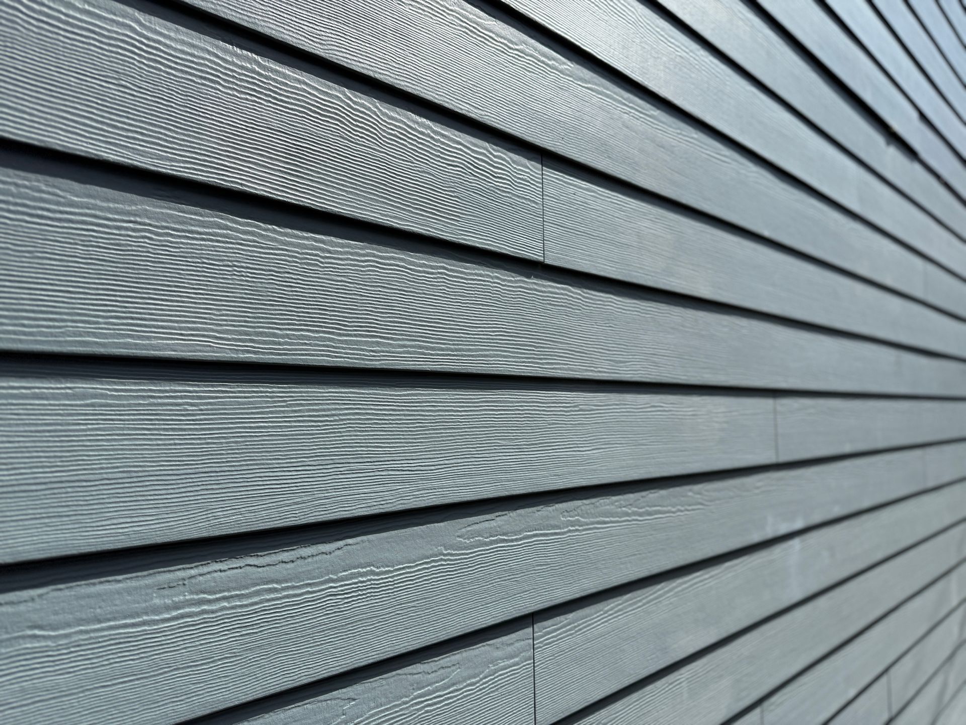 Gray horizontal siding with wood grain texture in close-up.