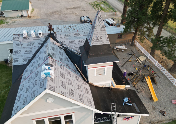 Worker measuring a rooftop with a pencil and tape measure, wearing a dark cap and jacket. Worker measuring a rooftop with a pencil and tape measure, wearing a dark cap and jacket.