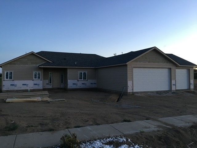 Single-story house with a two-car garage on a dirt lot at dusk