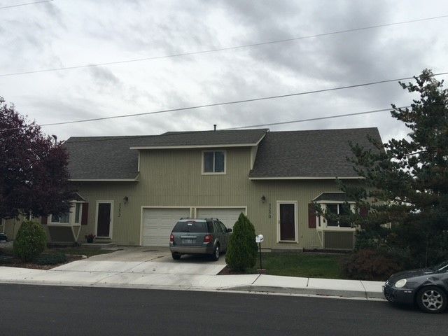 Suburban house with driveway, parked cars, and cloudy sky