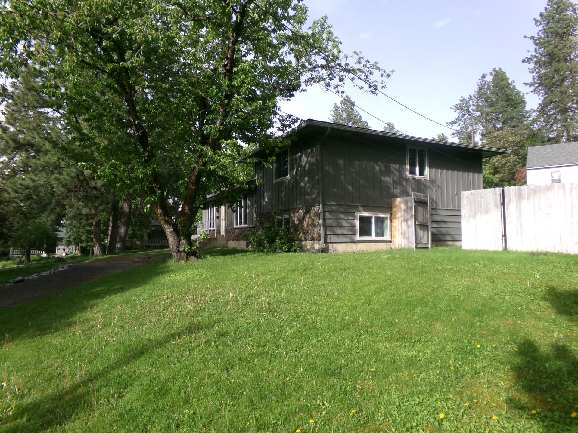 Aerial view of a brown shingled house roof with trees and a backyard nearby Aerial view of a brown shingled house roof with trees and a backyard nearby