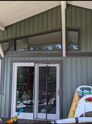 Sliding glass doors under a covered patio with high windows and green-gray siding