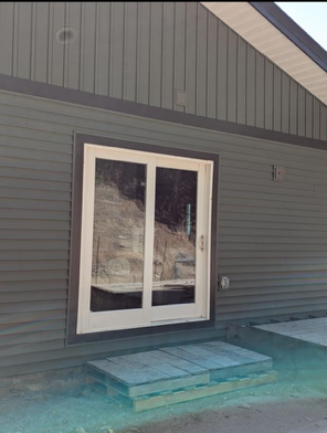 Gray house exterior with white French doors and a small teal step/porch.