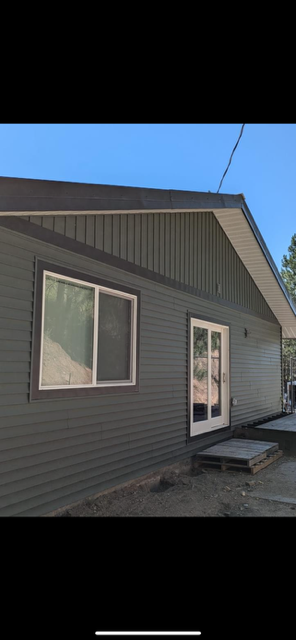A brown shingle roof on a house with a chimney and trees in the background A brown shingle roof on a house with a chimney and trees in the background