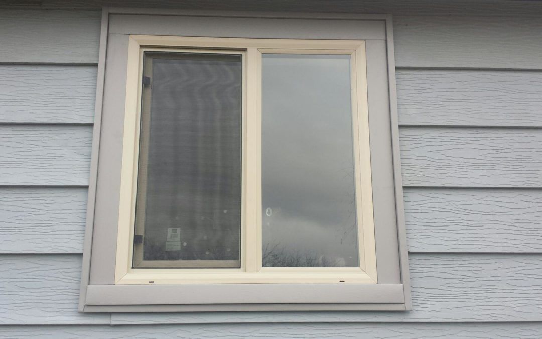 White-framed window with one open pane on a gray house exterior