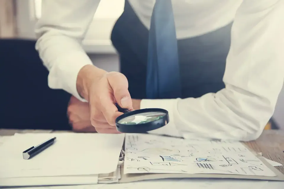 A man is looking through a magnifying glass at a piece of paper.