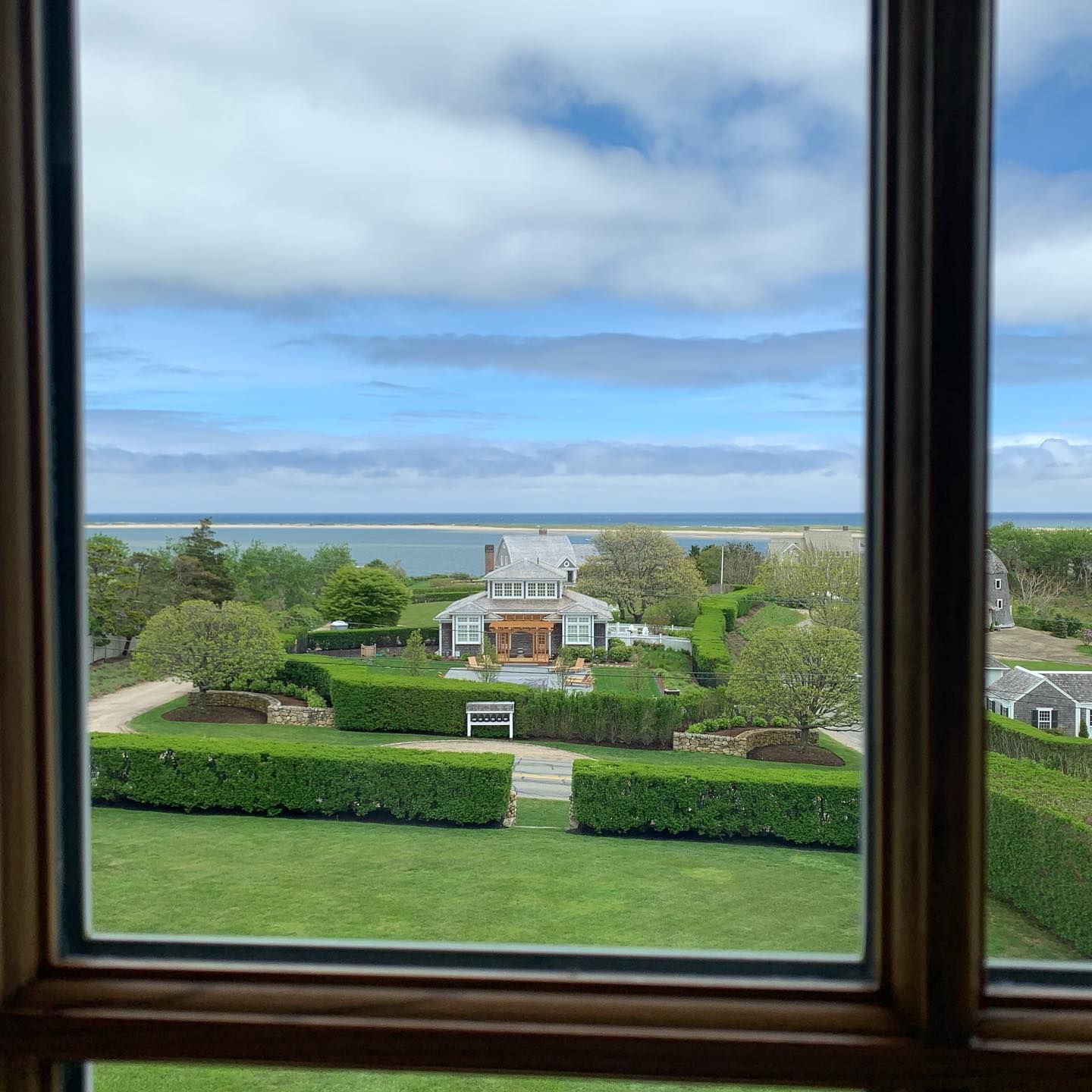 A view of a house and the ocean from a window.