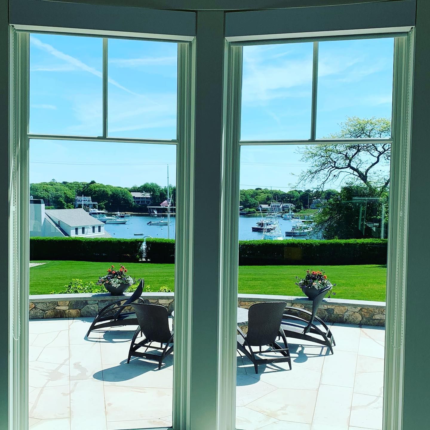 Two windows with a view of a patio with chairs and boats