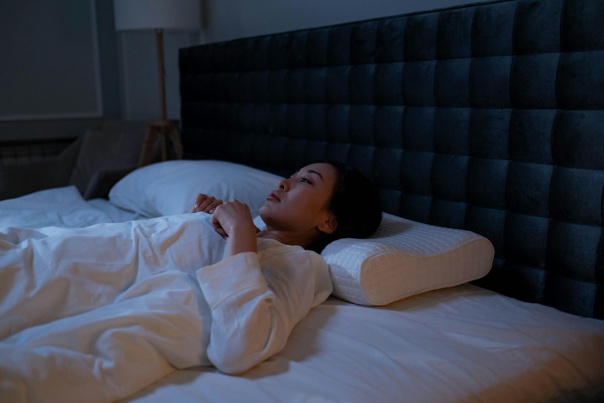 A woman wearing a sleep mask is laying on a bed.