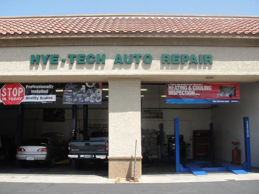 Hye-Tech Auto Repair storefront with open bays, vehicles inside, and signage advertising services.