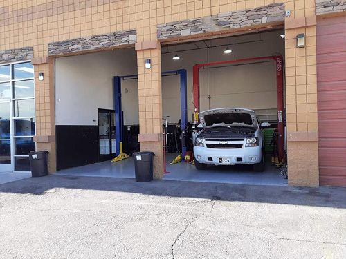 An auto repair shop with a white truck parked in a bay. Garage doors are open.