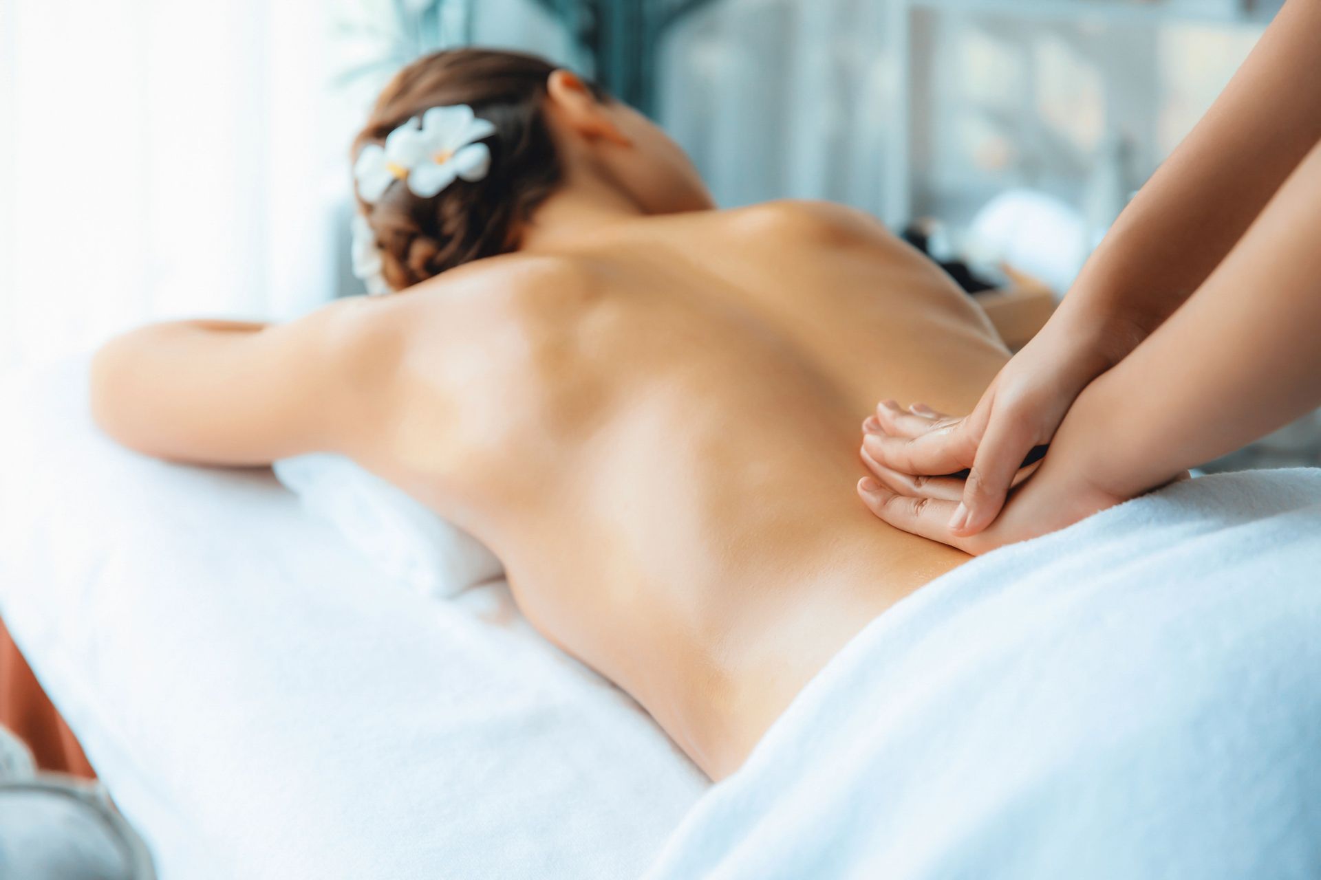 Massaggiatrice che massaggia la schiena di un cliente su un lettino da spa