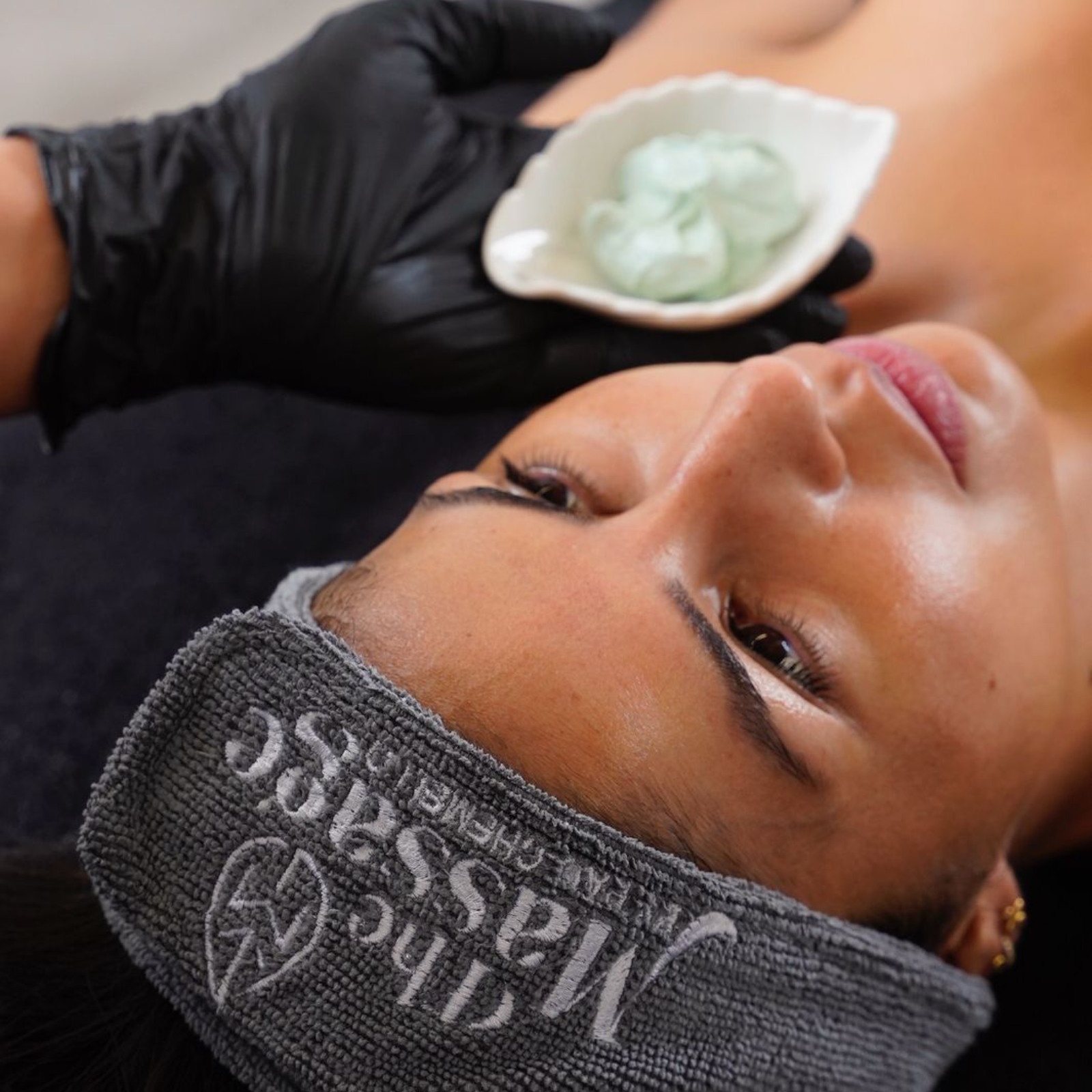 Persona tumbada durante un tratamiento facial en un spa, con una diadema negra