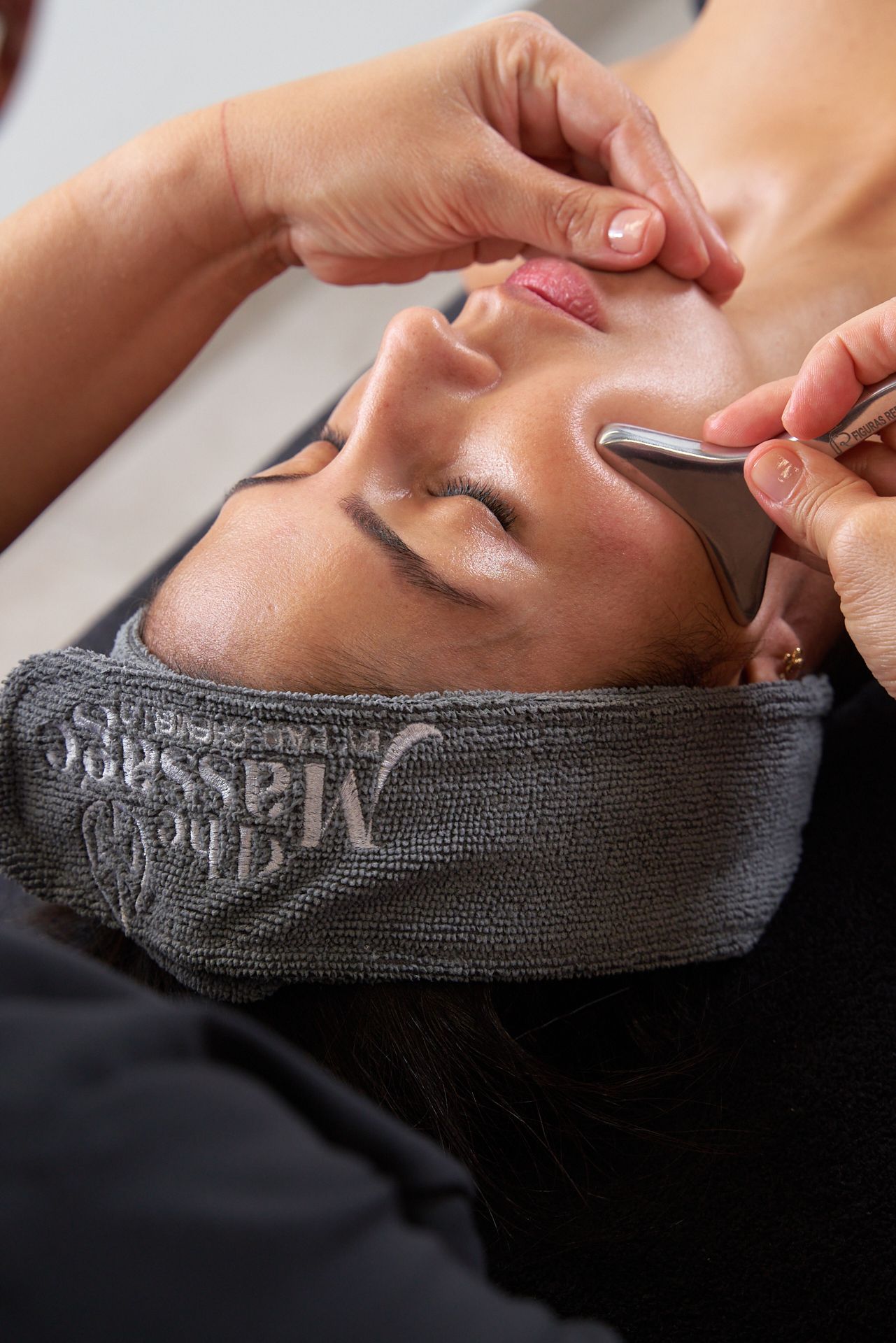 Primer plano de un tratamiento facial, en el que una profesional aplica el producto en la frente y la nariz de una clienta.