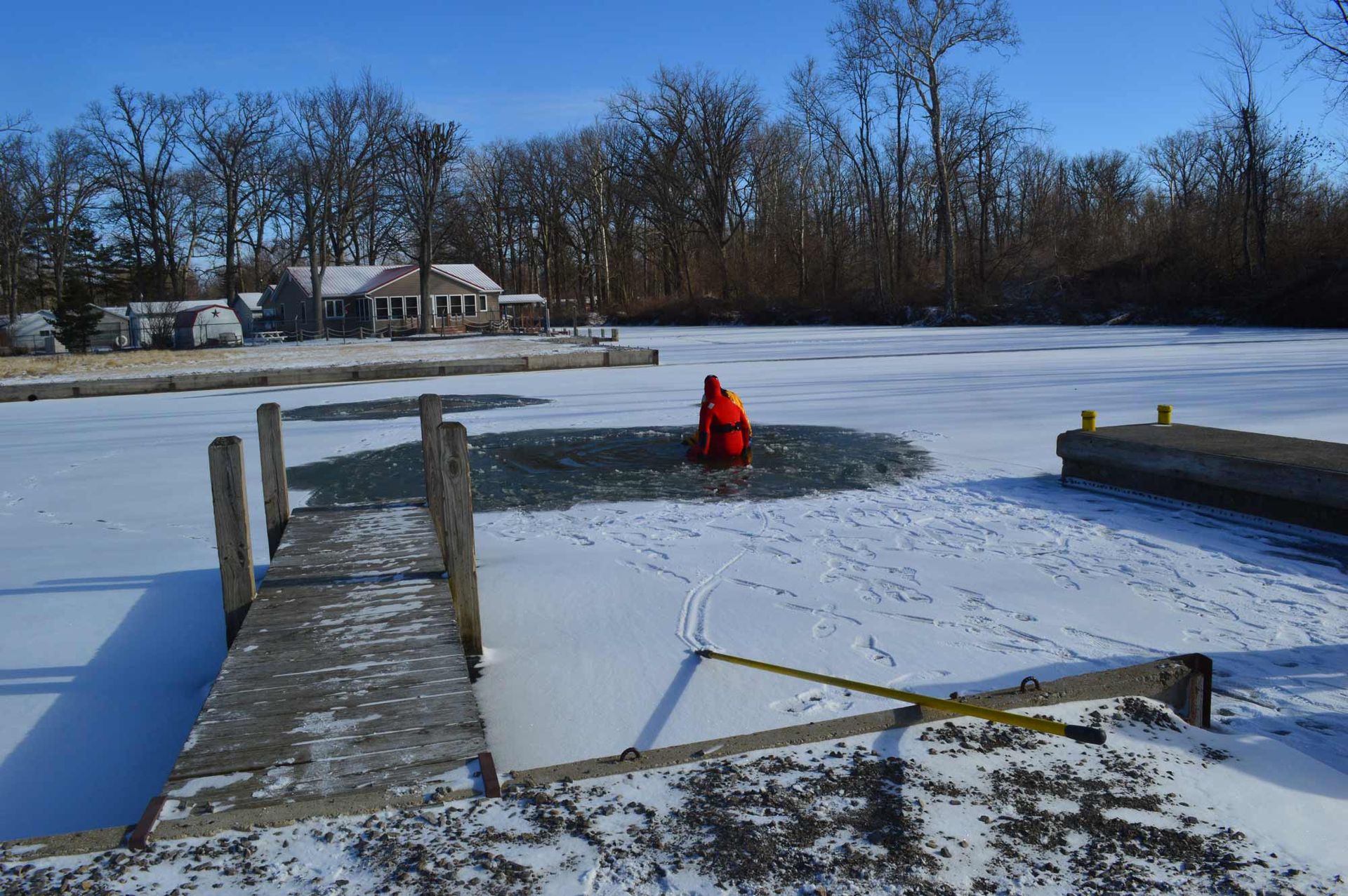 Snowy frozen pond with a person in a red jacket standing near the center dock area