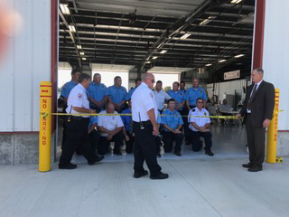 People gathered at a warehouse entrance during a ribbon-cutting ceremony.