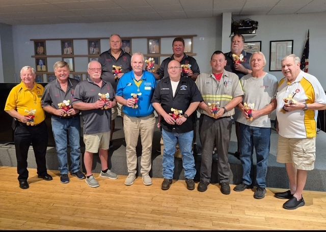 Group of people standing indoors on a stage, holding awards and posing for a photo.