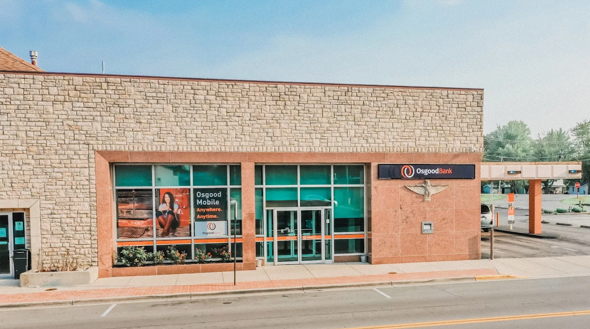 Front view of a stone building with large glass windows and a brick entrance under a clear sky