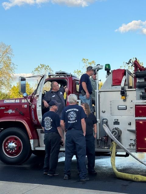 Firefighters gather around a red fire truck with hoses during a roadside response.
