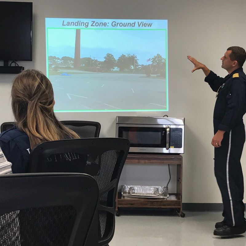 Instructor presents “Landing Zone: Ground View” slide to seated audience in a classroom.