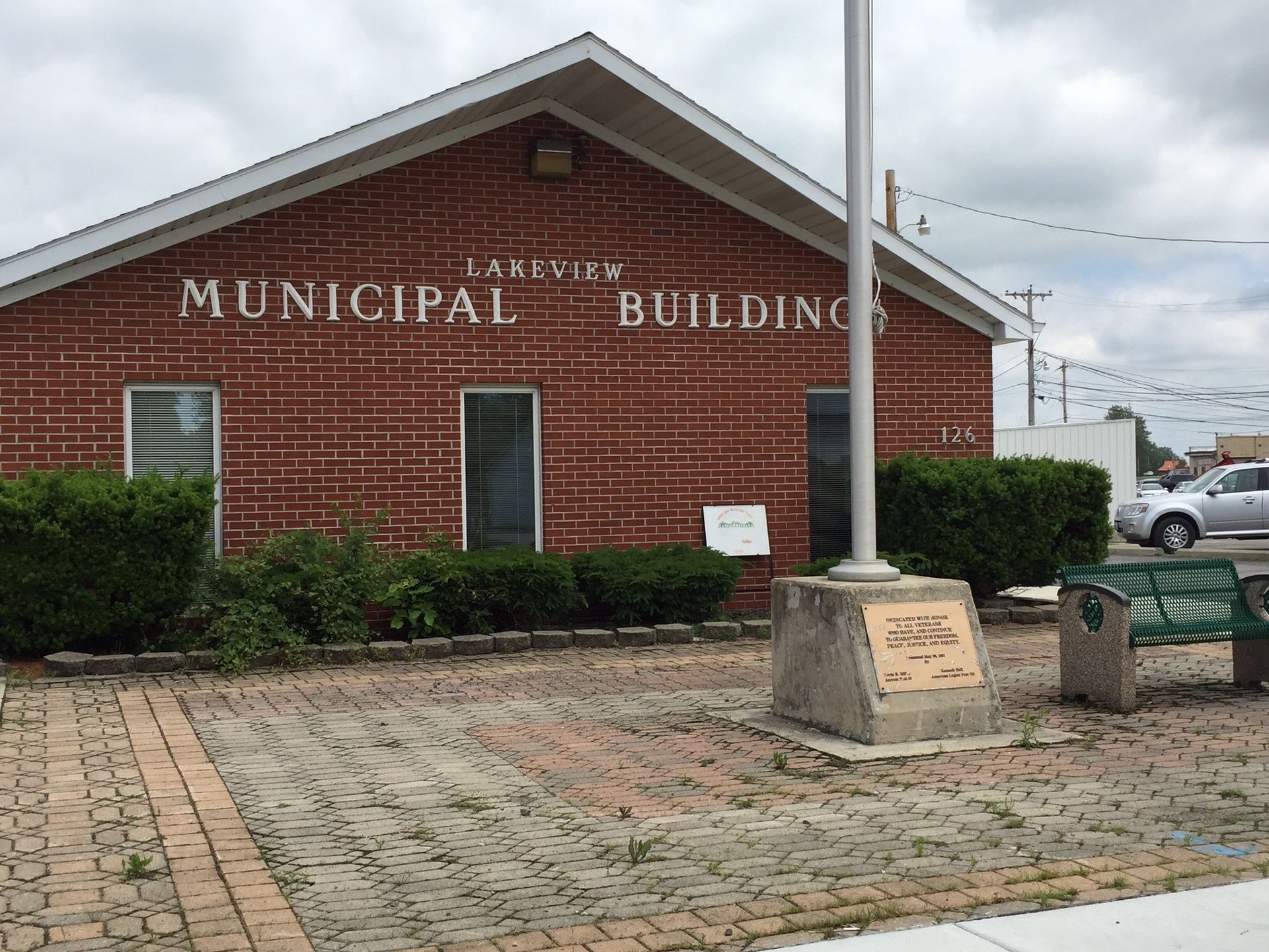 Municipal building with red brick exterior, white roof, and paved walkway in front