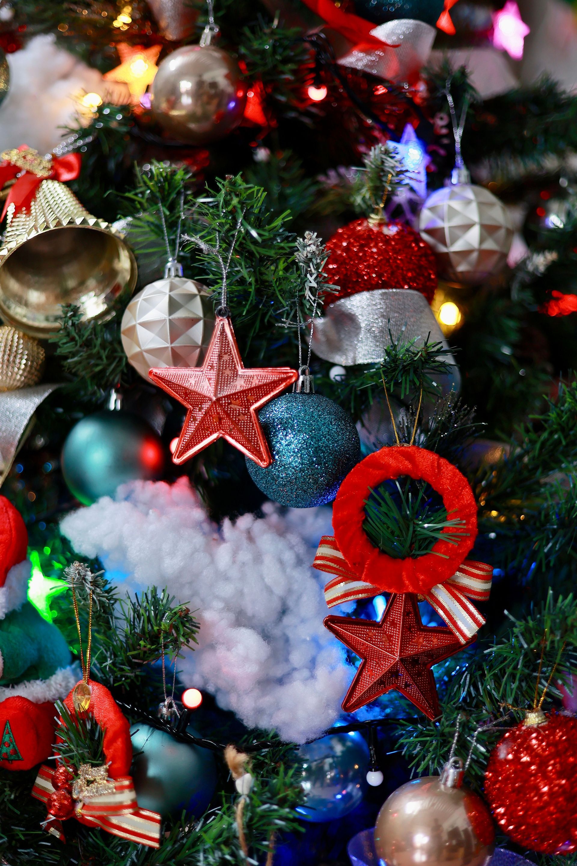 Decorated Christmas tree with red, silver, and blue ornaments, stars, and festive lights
