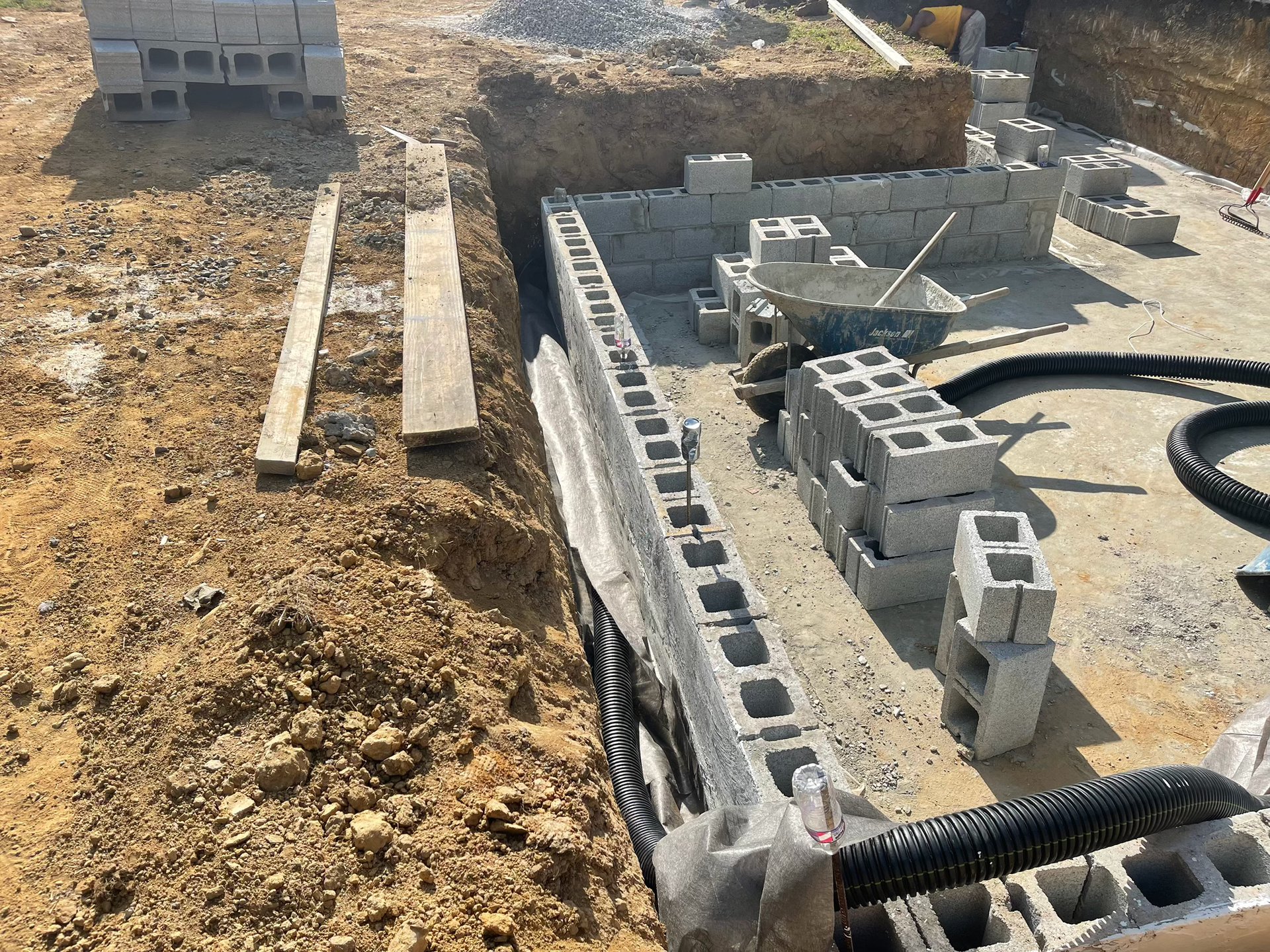 A brick wall is being built with a pile of dirt in the background
