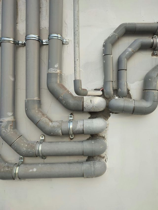 grey pipes of plumbing system outside of a house