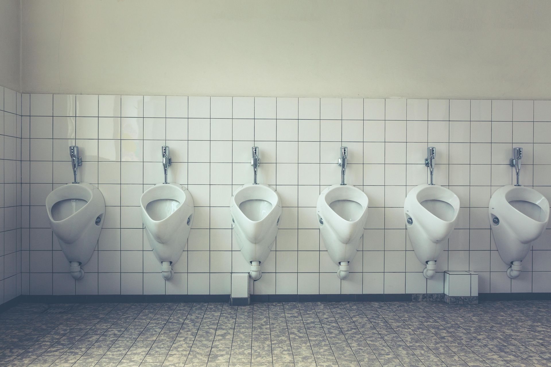 line of white mens urinals toilets in a business commercial building that were installed by gainesville plumbing