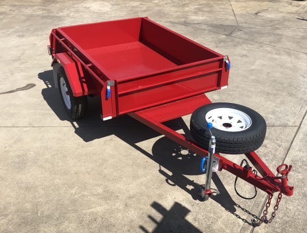 Red utility trailer with a spare tire on concrete.