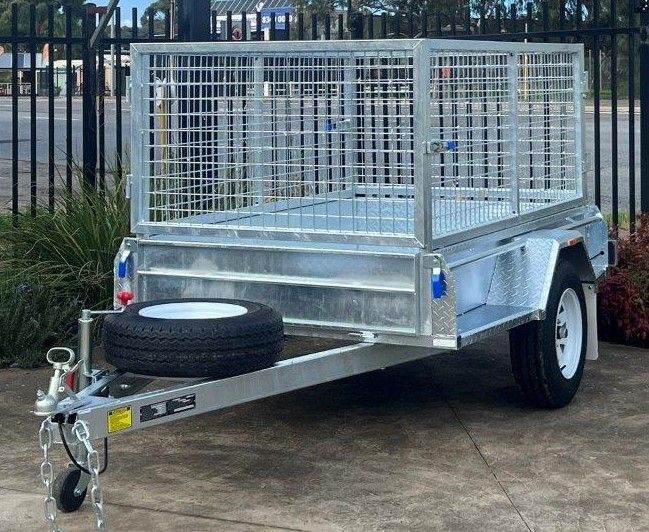 Galvanized steel box trailer with cage sides, spare tire, hitch, and wheels, outdoors.