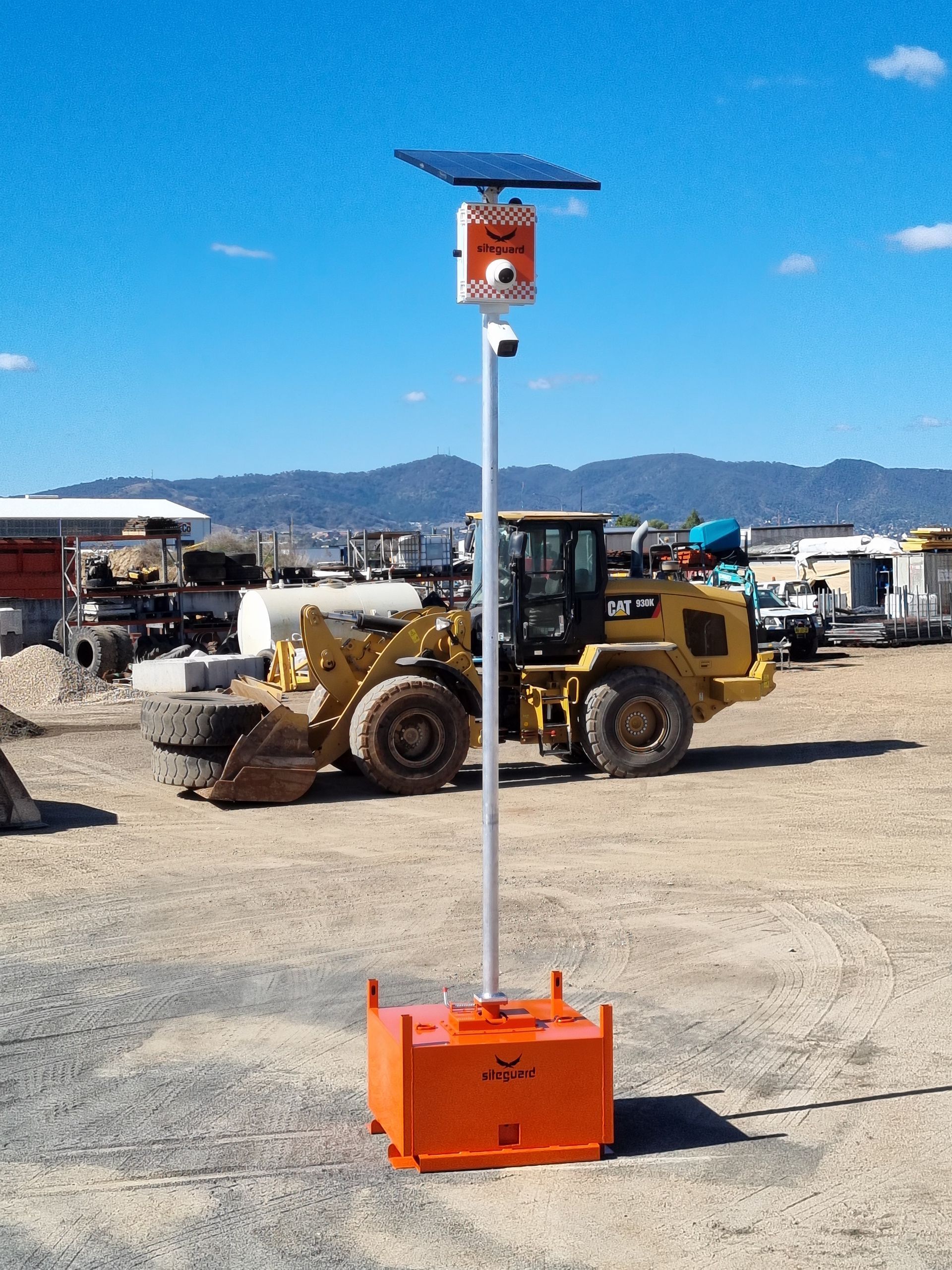 Orange solar-powered security camera system with a view of a construction site, including a bulldozer.