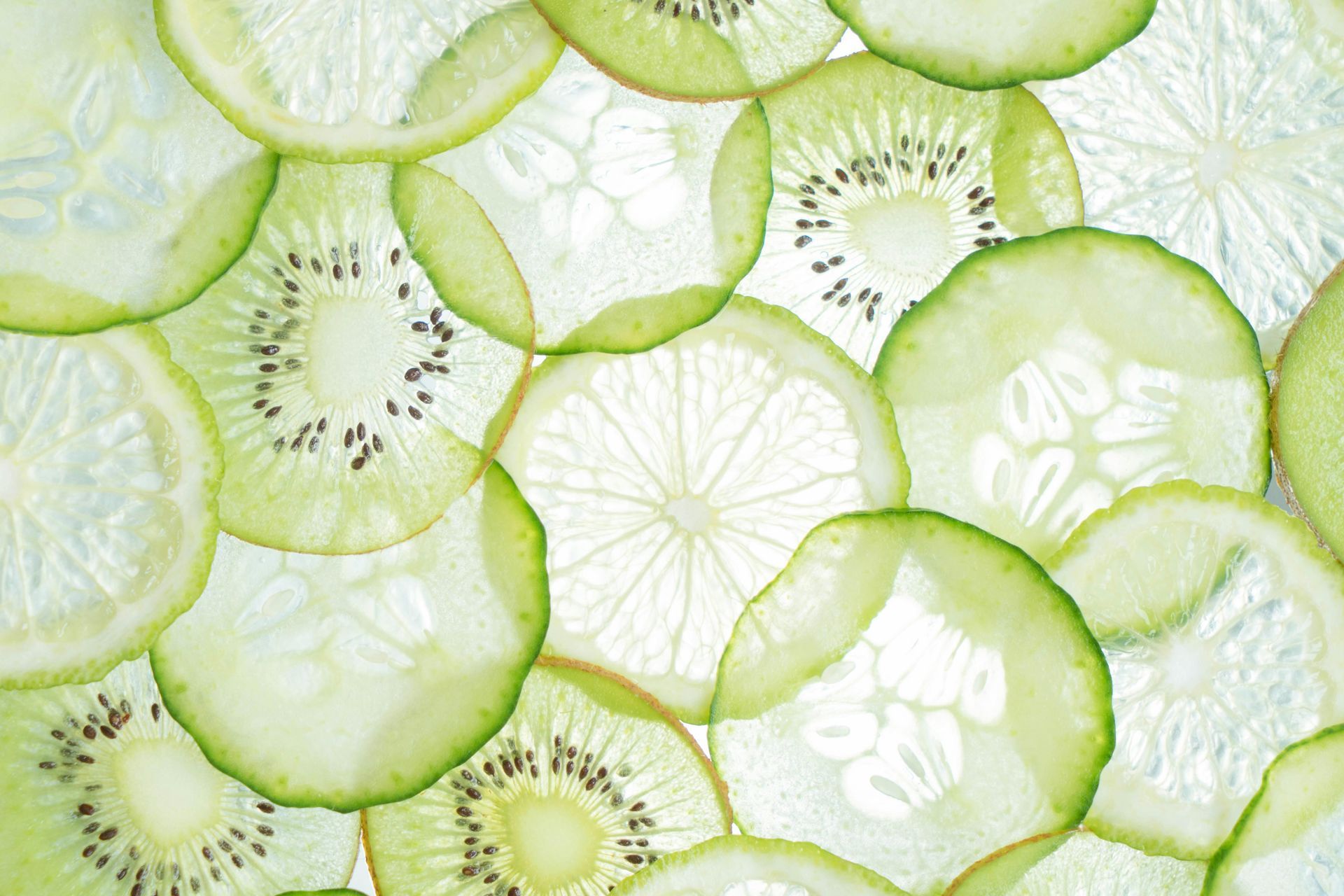 Fette sottili di kiwi, cetriolo e limone, disposte in un motivo verde traslucido.