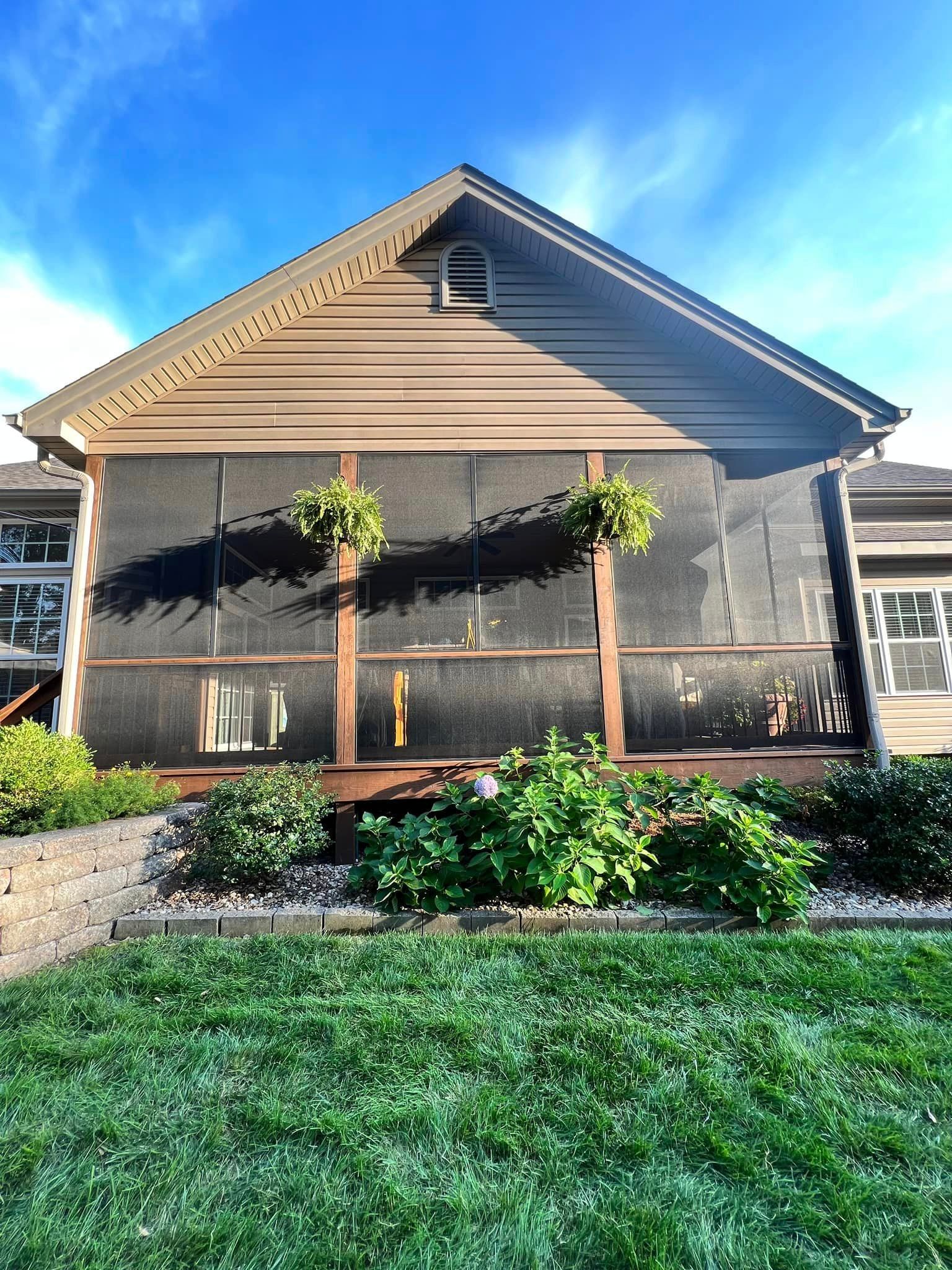 A house with a screened in porch and a lush green lawn in front of it.