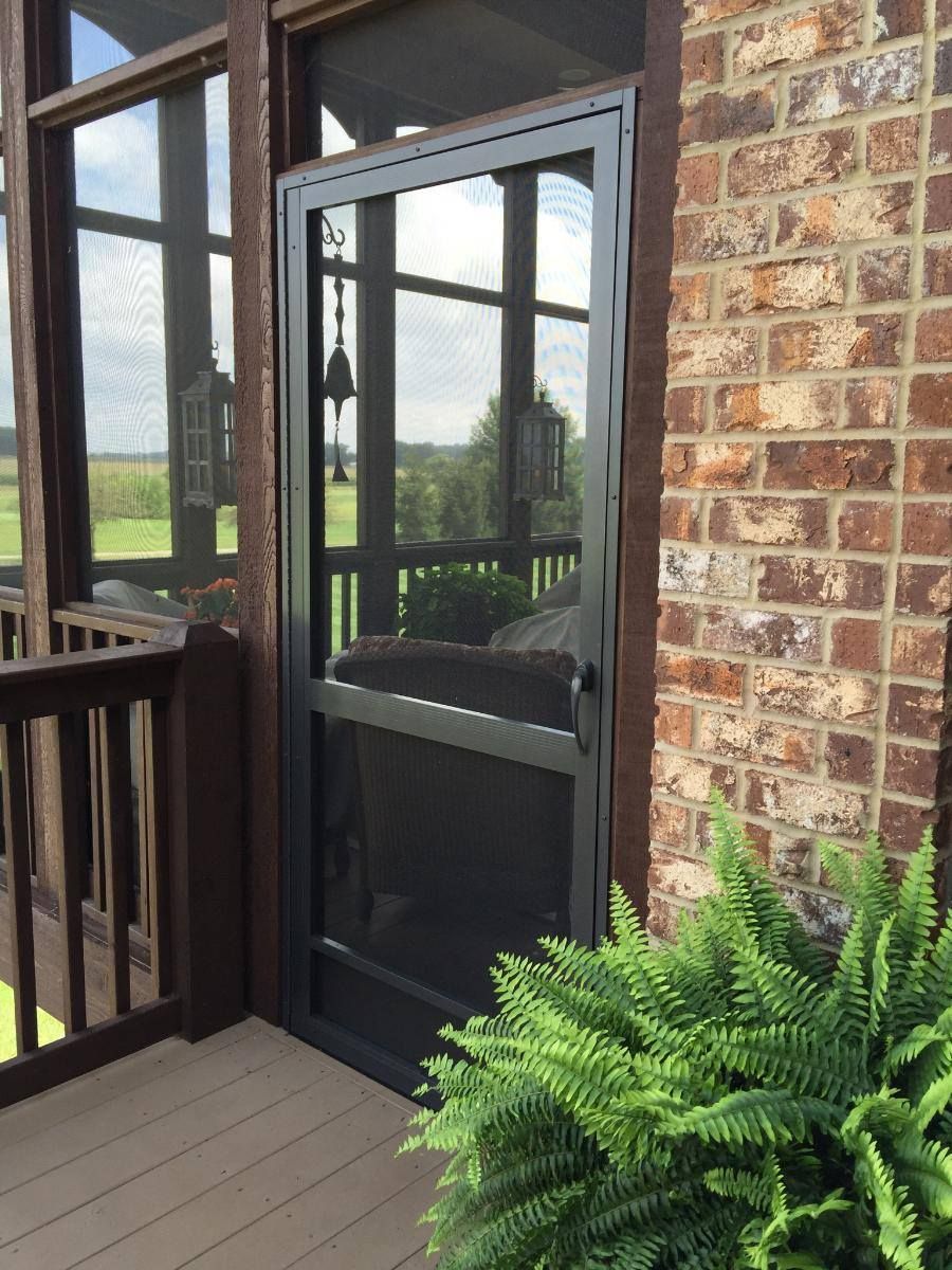 A screened in porch with a fern in front of it.
