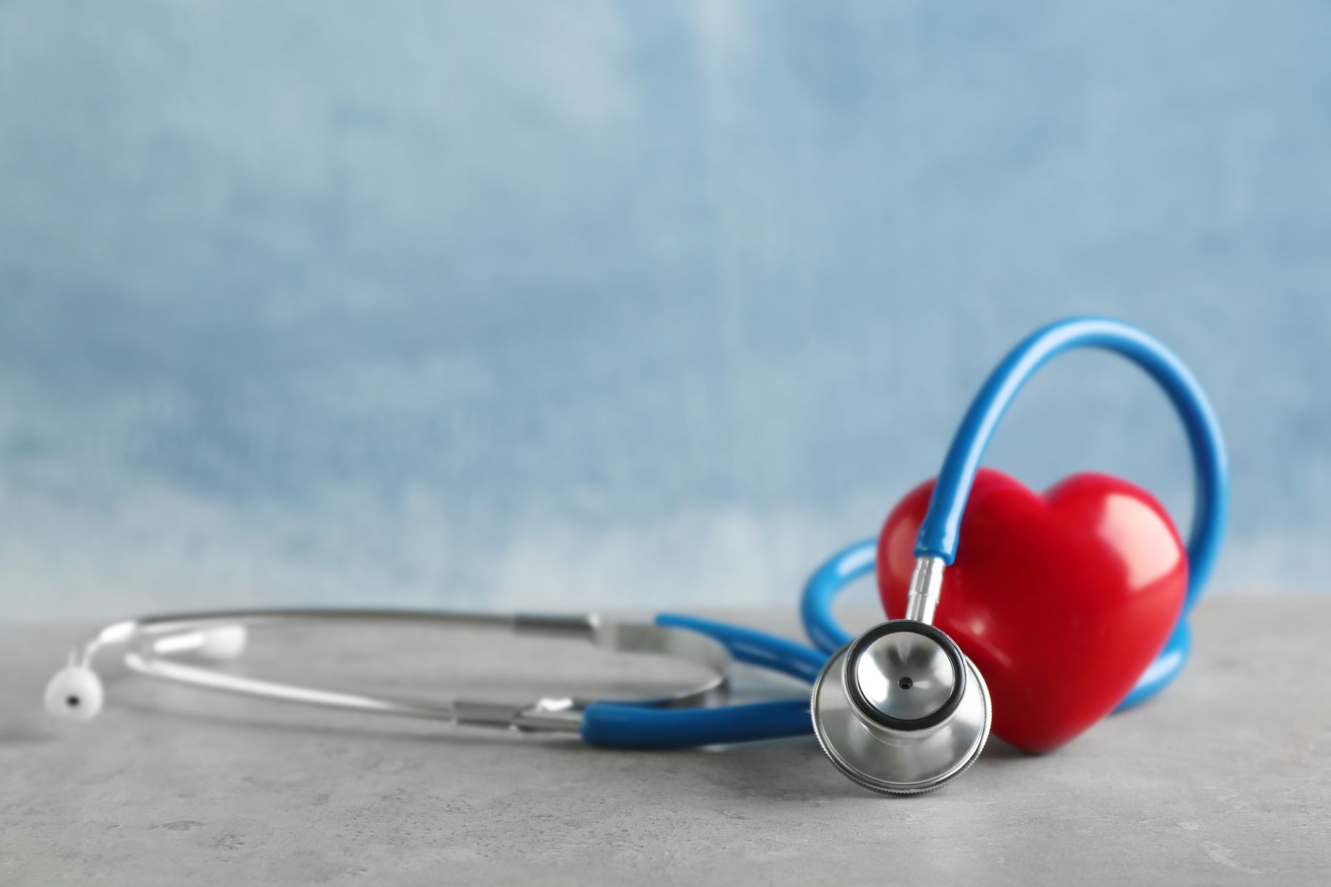 Medical stethoscope beside a glossy red heart symbol inside a modern health care clinic.