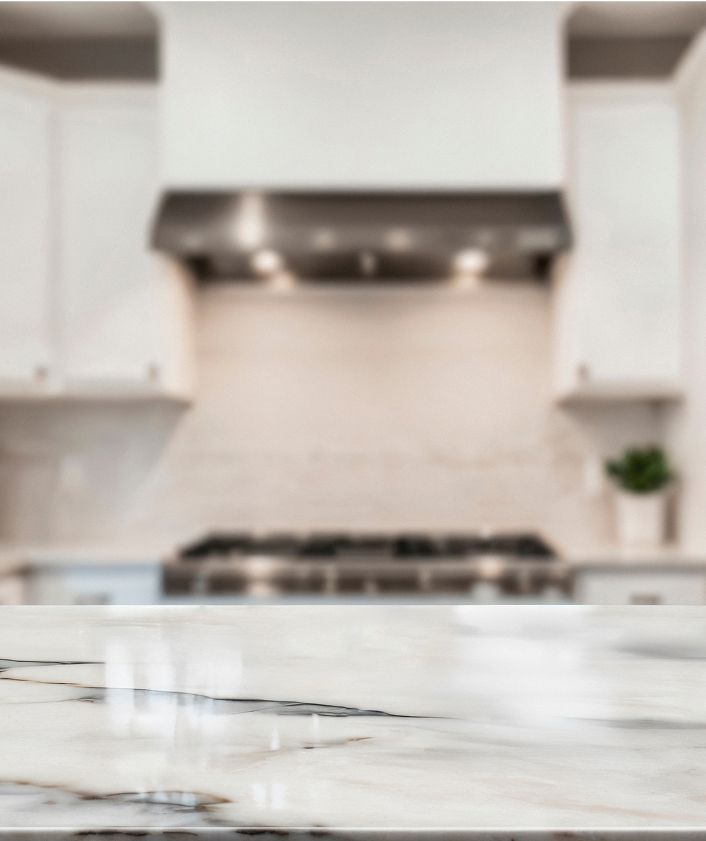 Marble countertop in a modern kitchen, with a stainless steel range hood and stove in the background.