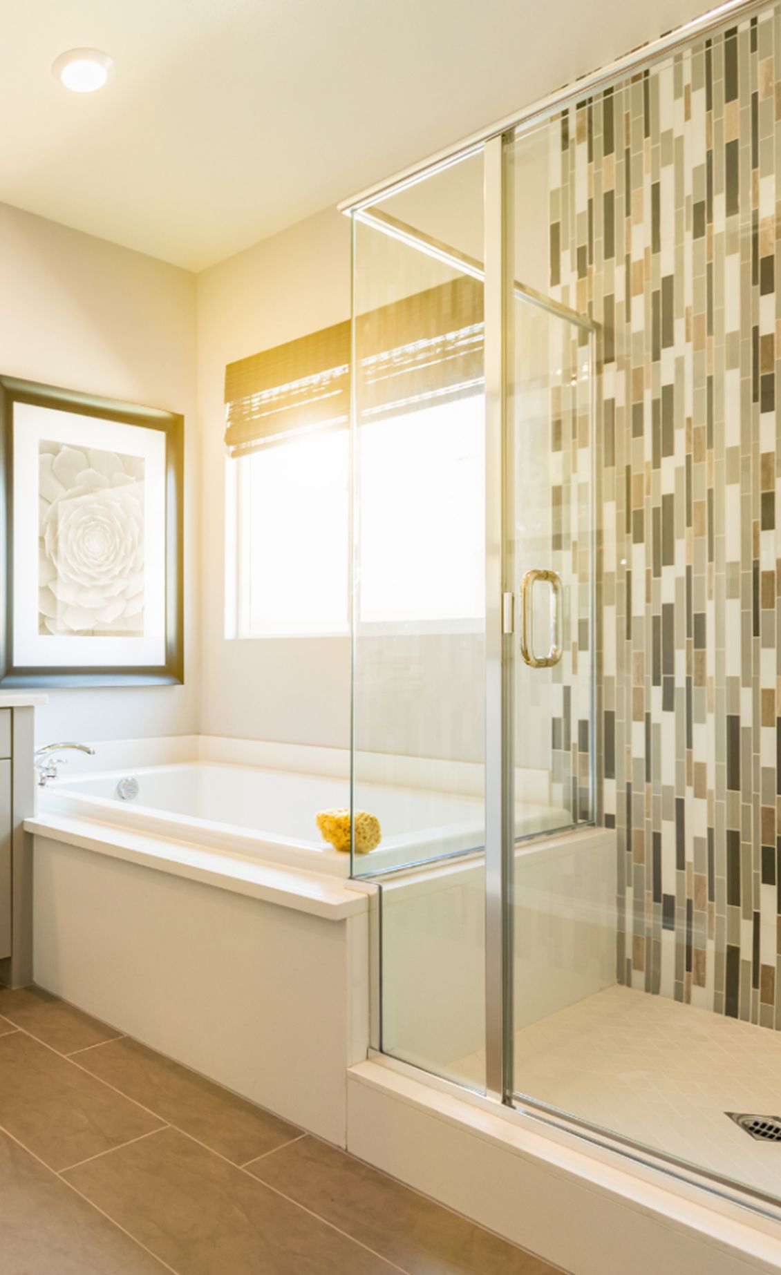 Bathroom with tub, glass shower, and mosaic tile wall; beige and brown tones.