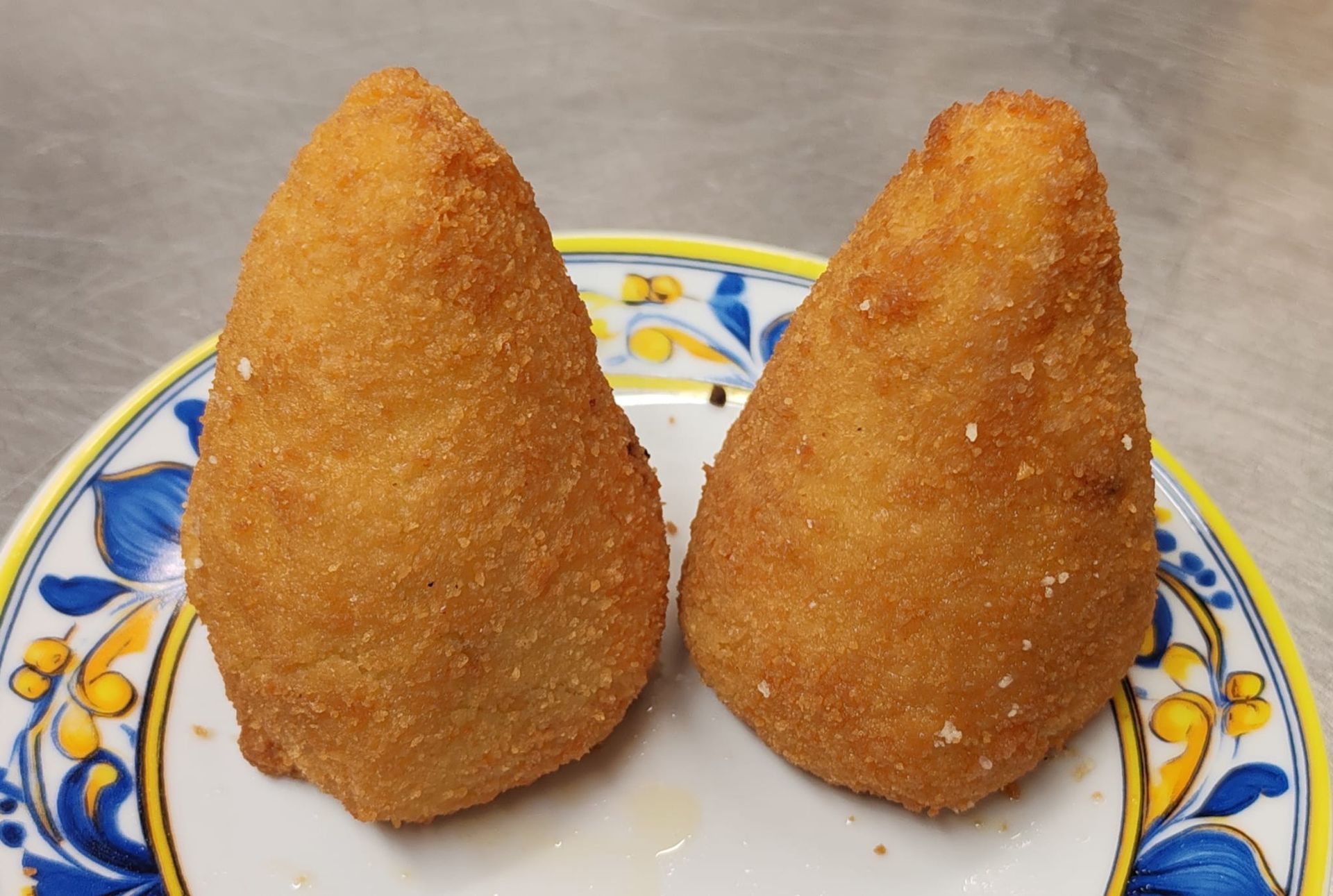 Piatto di pasta all'astice servito su un piatto bianco, con un bicchiere di vino bianco sullo sfondo.