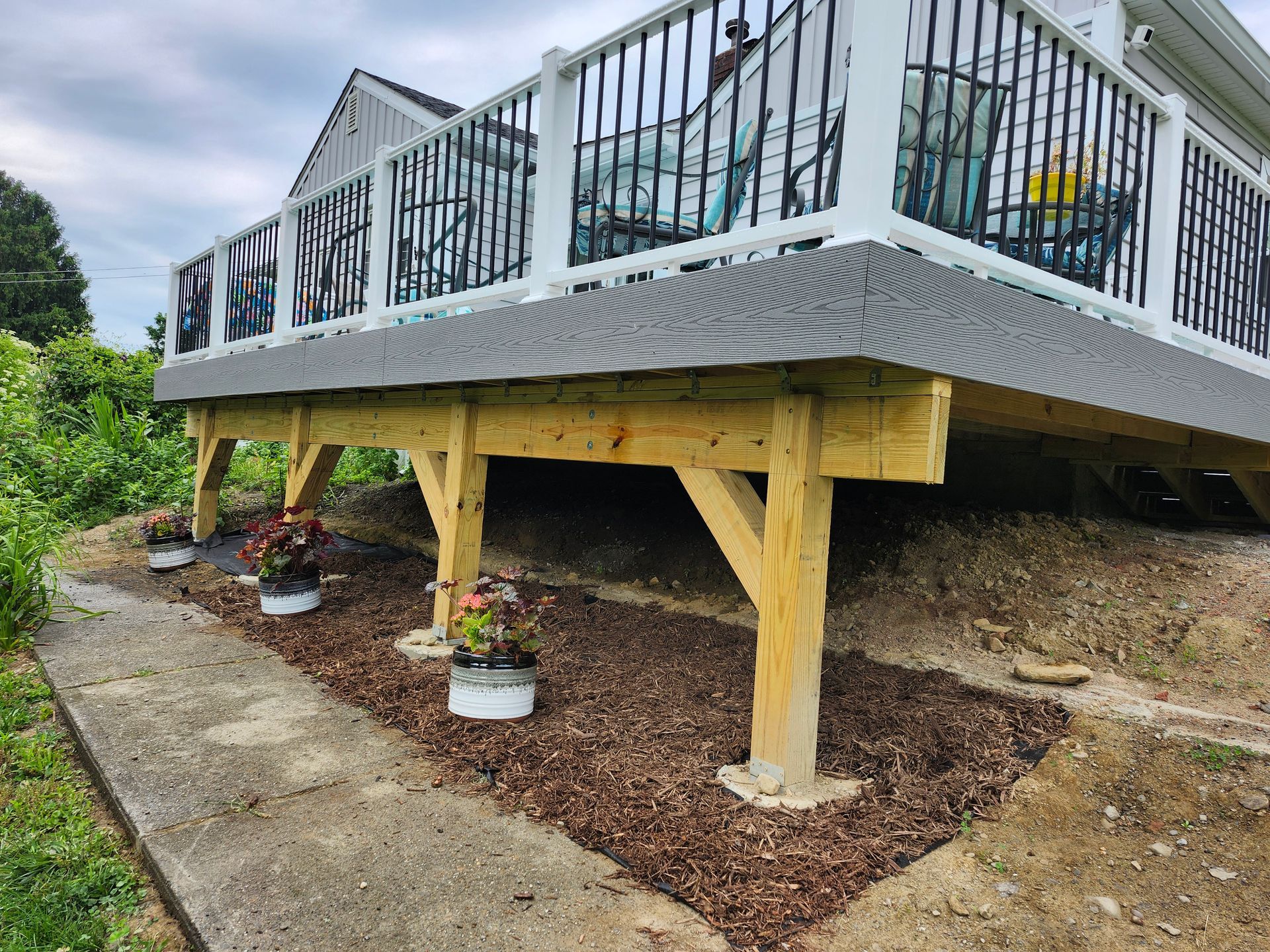 A wooden deck is sitting on top of a dirt hill next to a house.
